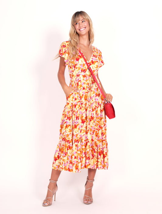 Bright patterned dress of yellow pink and red with pockets and a midi to maxi length and capped sleeves